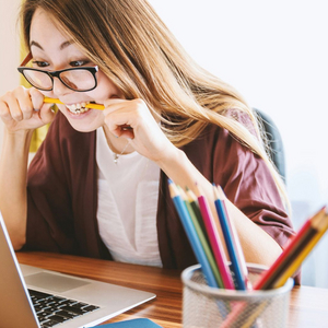Frau beißt auf Stift. Foto: Unsplash