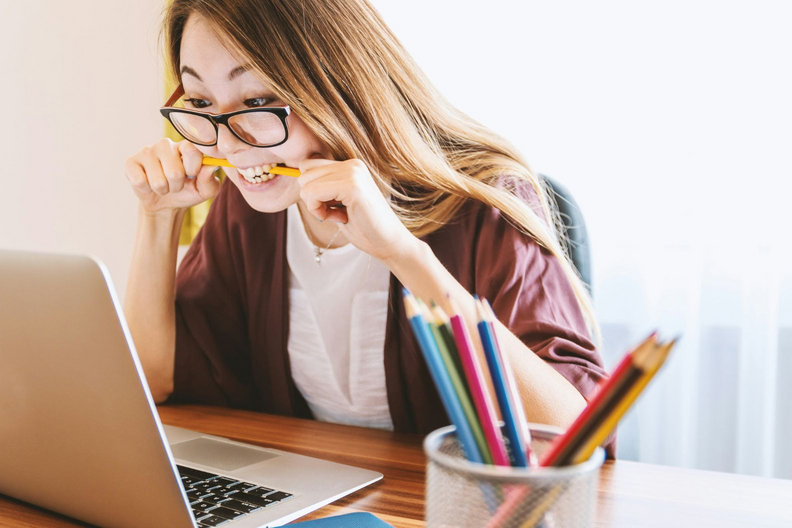 Frau beißt auf Stift. Foto: Unsplash